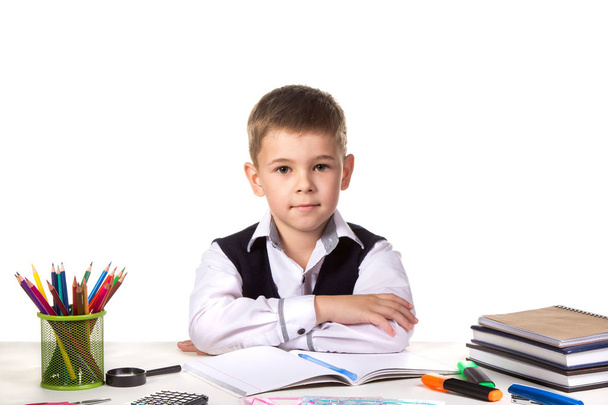 Smart serious excellent pupil sitting still at the desk with white background - Photo, Image