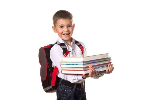 Χαμογελαστό αγόρι σχολείο με σακίδιο κρατώντας σημειωματάρια, σε λευκό φόντο - Φωτογραφία, εικόνα