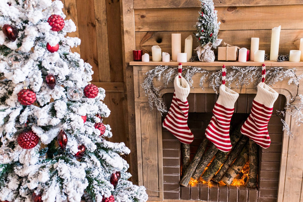 Stivali di tre Capodanno appesi vicino al camino vicino all'albero di Natale - Foto, immagini