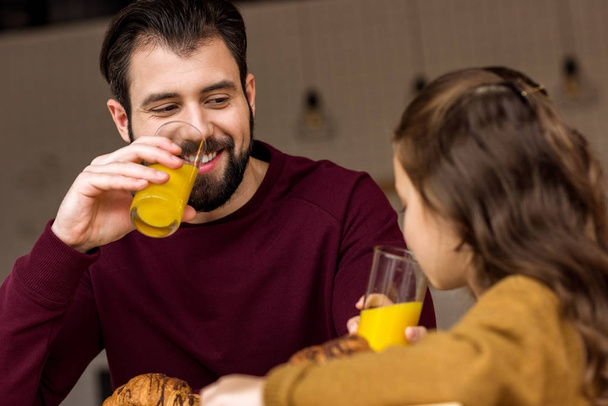 Isä ja tytär juovat appelsiinimehua kahvilassa
 - Valokuva, kuva