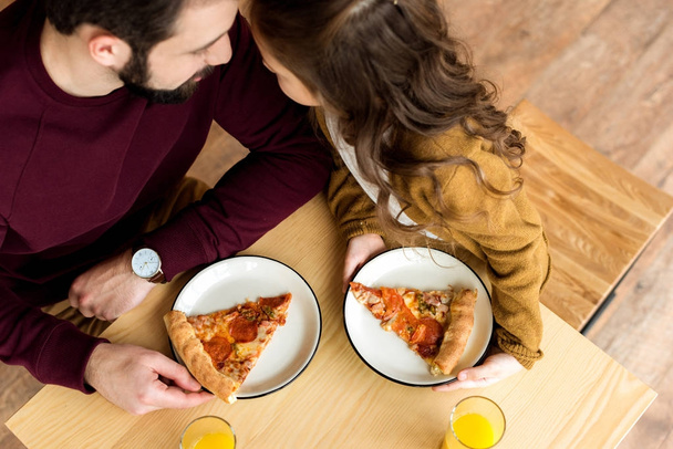 vista aérea del padre y la hija hablando y sentado en la cafetería con pizza
 - Foto, imagen