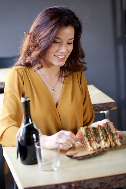 young woman eating a club sandwich in a bar - Zdjęcie, obraz