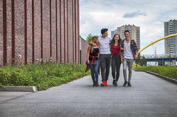 Группа друзей, гуляющих вместе под открытым небом в городе, разговаривающих и смеющихся
 - Фото, изображение