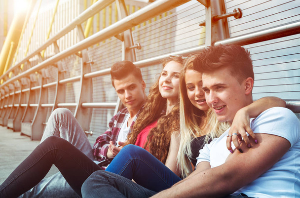 Group of friends sitting together outdoor on urban scenery - Foto, imagen