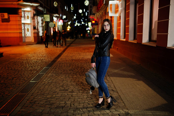 Night portrait of girl model wear on glasses, jeans and leather  - Фото, изображение