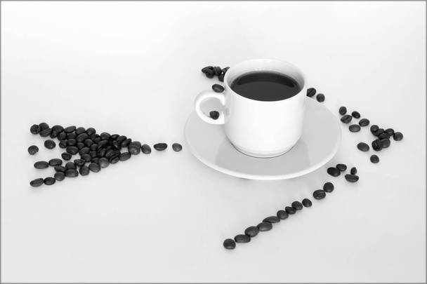 φλιτζάνι καφέ και κόκκους καφέ με μορφή βέλη σε λευκό φόντο - Φωτογραφία, εικόνα