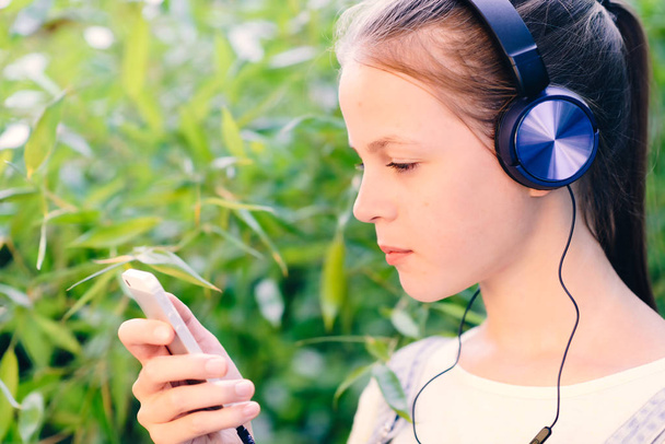 Linda chica escuchando música con auriculares al aire libre
 - Foto, Imagen