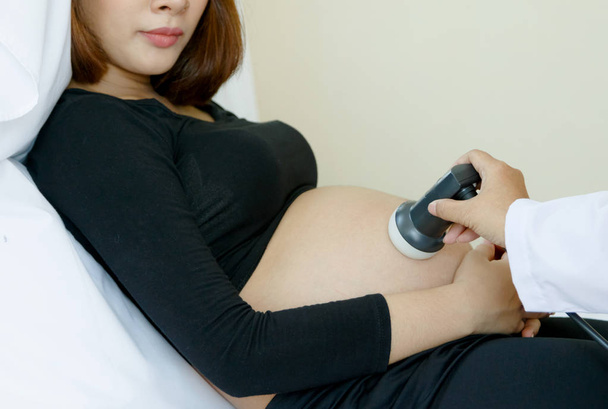 Dokter bewegende echografie Transducer op zwangere vrouw buik - Foto, afbeelding