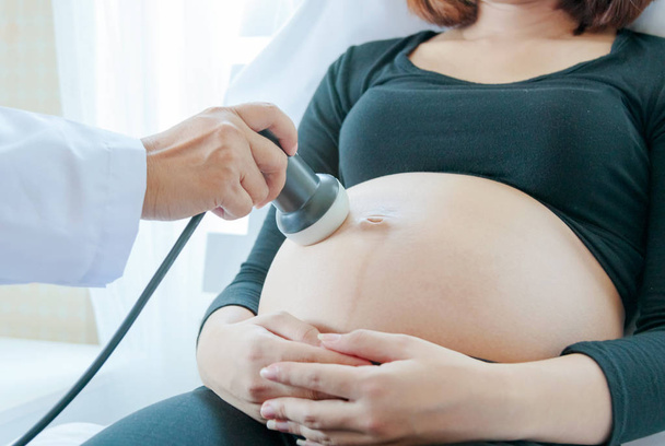 Hamile kadının karnında üzerinde hareketli ultrason dönüştürücü doktor - Fotoğraf, Görsel