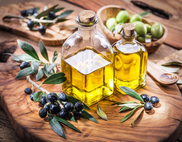 Olivenöl und Beeren auf dem Olivenholztablett.  - Foto, Bild