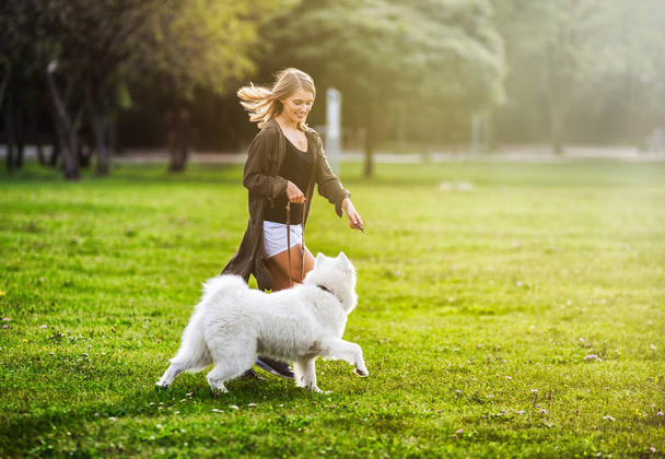 Pretty girl playing with samoyed dog during walk outdoor - Foto, imagen
