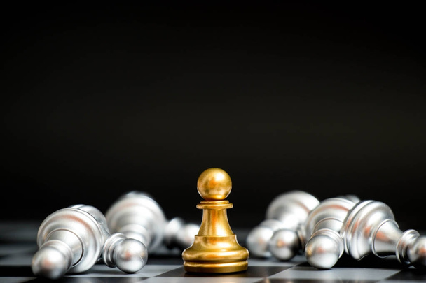 Золотая пешка в шахматной игре лицом к лицу с другой серебряной командой на черном фоне (Концепция стратегии компании, победа бизнеса или решение) - Фото, изображение