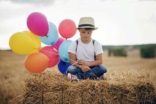 niño triste con globos en el campo
 - Foto, imagen