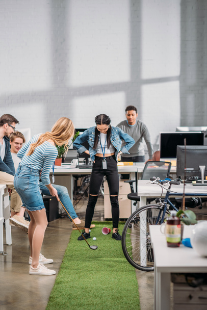 wesoły kolegami grając w minigolfa w nowoczesnym biurze  - Zdjęcie, obraz