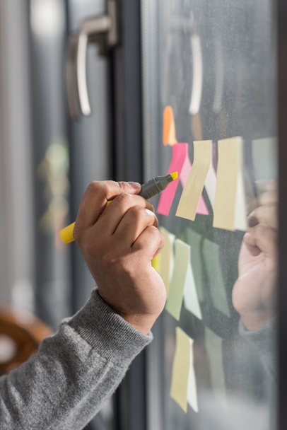 cropped image of man making notes on stickers at window - 写真・画像