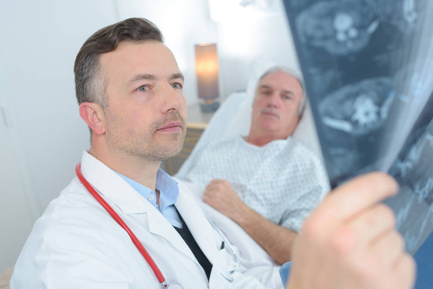 médecin montrant une radiographie à un patient âgé à l'hôpital - Photo, image