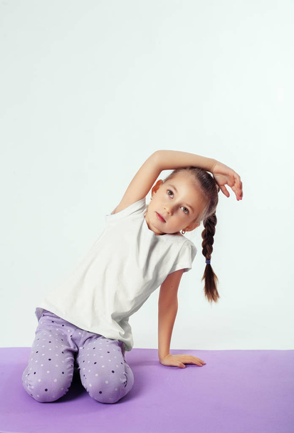 Little girl makes sports exercises. The concept of sport - Foto, Imagen