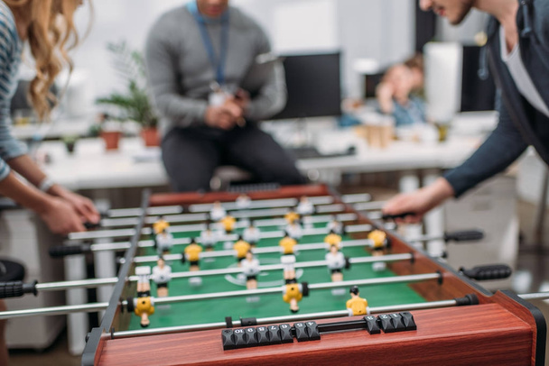 cropped image of people playing in table soccer at modern office - Foto, Imagen