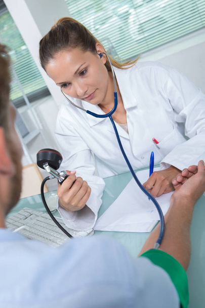 doctor testing blood pressure to a senior patient - Foto, afbeelding