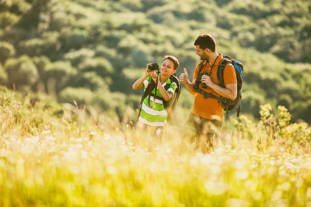 Father and son are hiking in nature in summer. Boy is photographing.  - Photo, Image