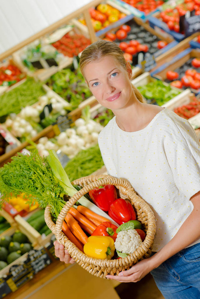 Lady holding wicker basket of vegetables - Фото, изображение