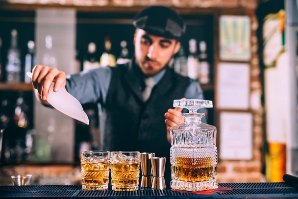 close up of elengant bartender pouring whiskey and ice on fresh cocktails in modern bar - Φωτογραφία, εικόνα