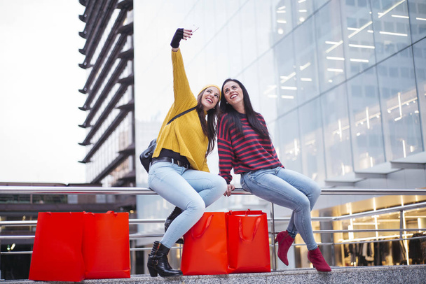 Two women friends taking a selfie in street after shopping - Photo, Image