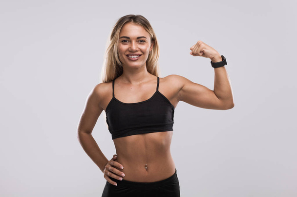 Smiling fit woman showing bicep - Foto, immagini