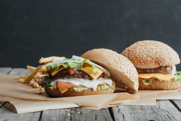 gustosi cheeseburger fatti in casa su carta da forno con patatine fritte
 - Foto, immagini