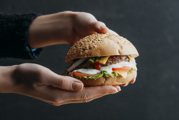 cropped view of female hands with traditional american homemade burger - Foto, Imagen
