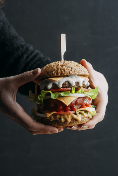 cropped view of female hands with big homemade cheeseburger - Foto, Bild