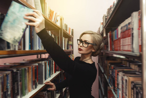 a könyvtárban egy fiatal nő úgy dönt, hogy egy könyv - Fotó, kép
