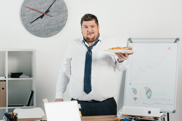 fat businessman with junk food in office - Photo, Image