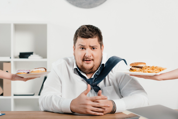 hombre de negocios con sobrepeso elegir comida chatarra para el almuerzo
 - Foto, Imagen
