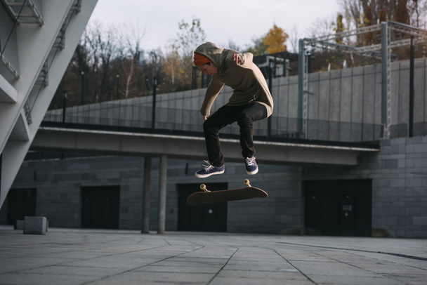 young skateboarder performing jump trick in urban location - Foto, Imagen