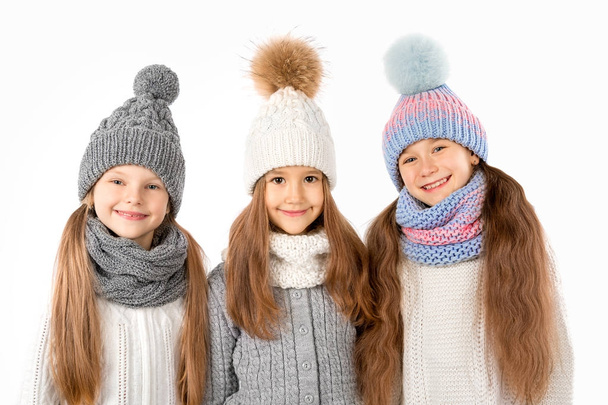 Group of cute kids in winter warm hats and scarfs isolated on white. Children winter clothes - Photo, Image