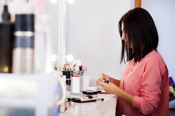 Beauty woman applying makeup. Beautiful girl looking in the mirr - Foto, Imagem