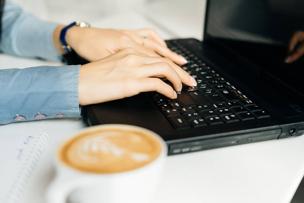 girl freelancer working behind laptop in cafe, next to mug with coffee - Photo, image