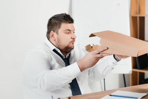 overgewicht zakenman pizza eten op werkplek - Foto, afbeelding
