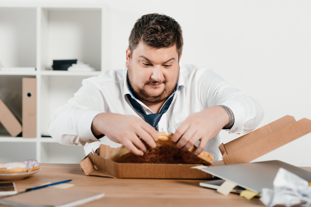 fat businessman eating pizza for lunch at workplace - Foto, Bild