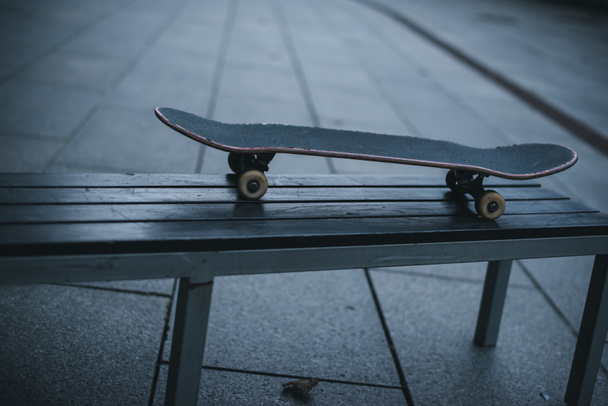old skateboard standing on bench outdoors - Photo, Image