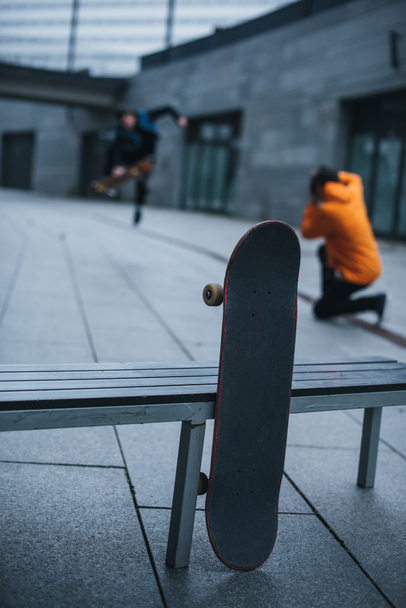 Skateboarder fotografieren Tricks mit Skateboard an Bank im Vordergrund angelehnt - Foto, Bild
