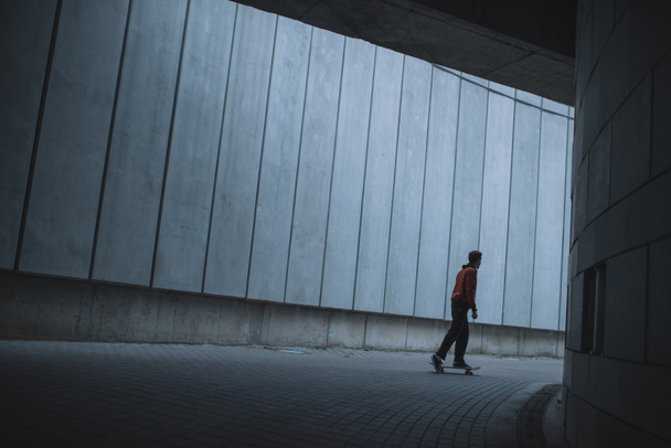 skateboarder riding at urban location with grey concrete walls - Fotó, kép