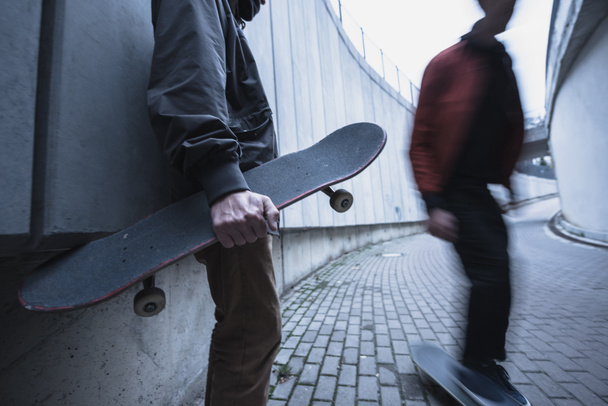 cropped shot of skateboarders in street outfit spending time in urban landscape - Foto, Imagem