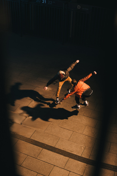 високий кут зору скейтбордистів робити той же трюк разом
 - Фото, зображення