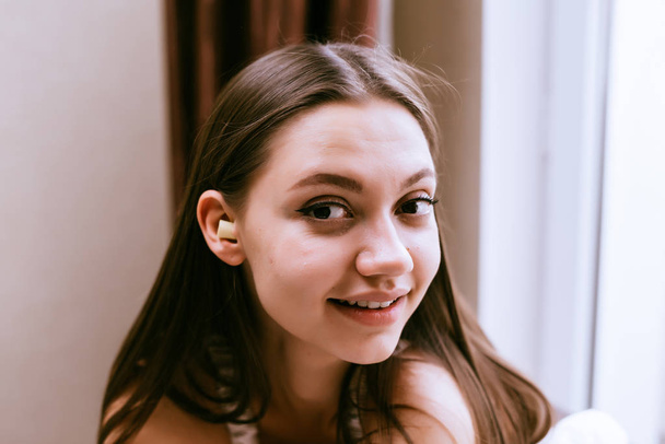 cute young girl smiling, in ear-earplugs against noise - Zdjęcie, obraz