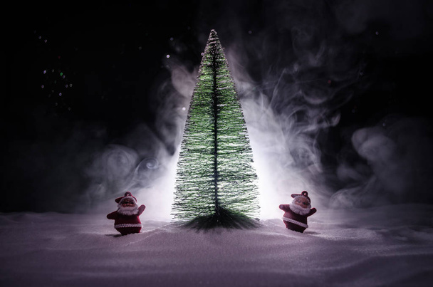 Boldog baba Mikulás karácsony fa és a hó. Színes bokeh háttér. Mikulást és karácsonyt modell szám játék a sötét tónusú - Fotó, kép