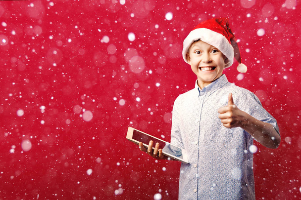 young santa boy making the ok thumbs up gesture while holding a tablet - Fotografie, Obrázek