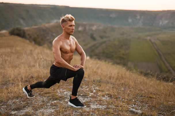 Bare-chested man lunging in nature - Foto, Bild