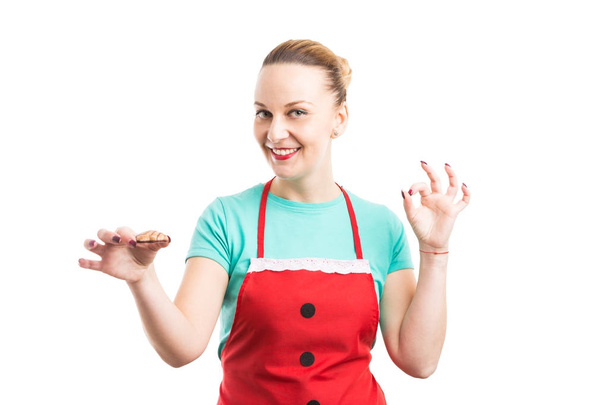 Lächelnde Frau mit roter Schürze hält Lebkuchen in der Hand und zeigt Oka - Foto, Bild